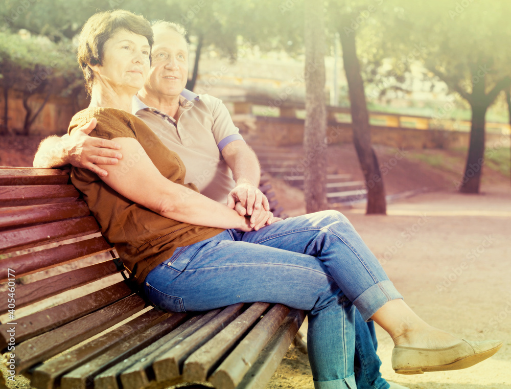 mature man with a woman sitting on bench mature man with a woman sitting on bench