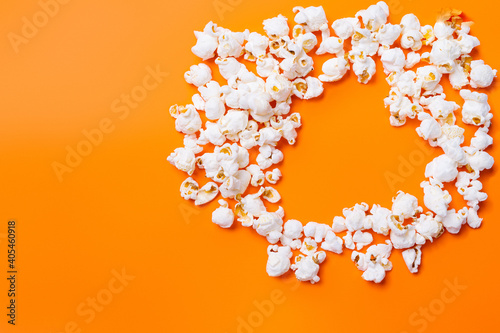 Scattered popcorn in the shape of heart on orange background. Time spent by loved ones. Movie and popcorn.