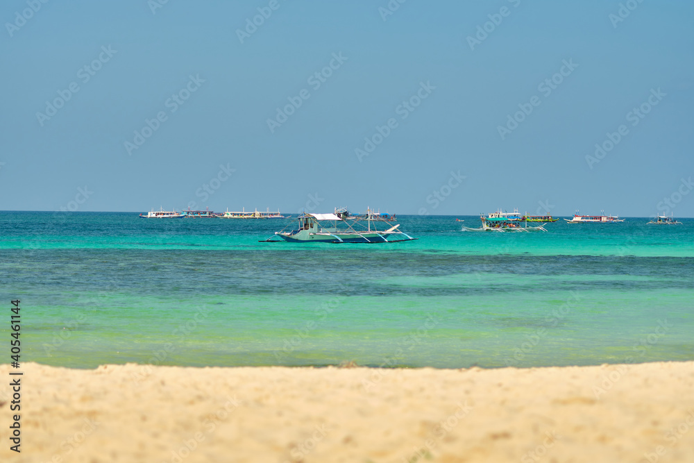 Empty White beach of Boracay island in the daytime. No Chinese tourists because of the coronavirus. Boats in the sea carry tourists.