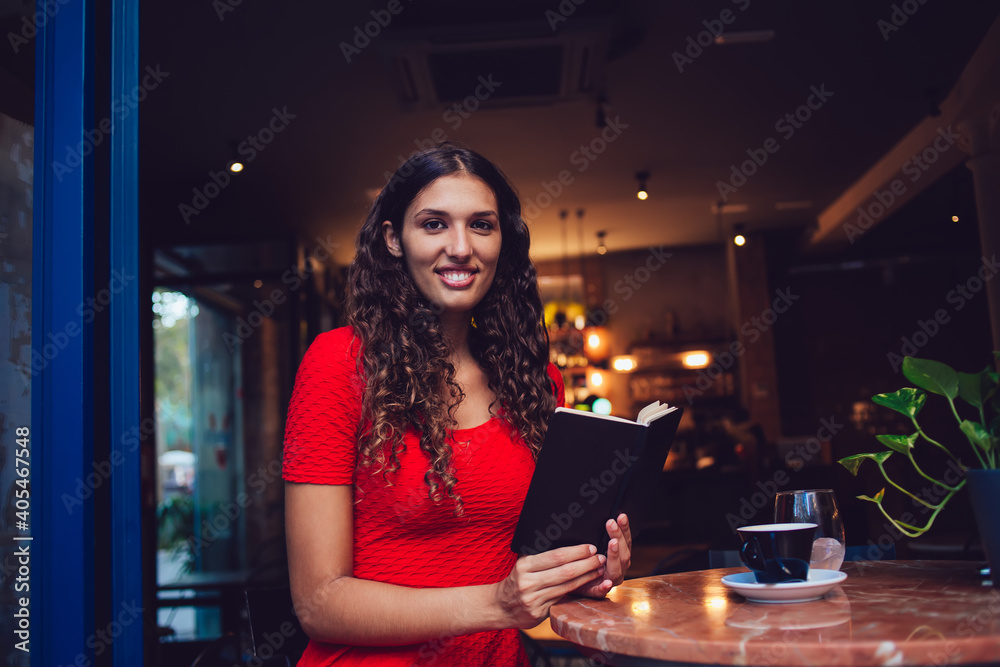Smiling Hispanic woman with book in cafe
