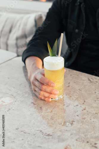 Wallpaper Mural A tropical yellow sour cocktail. A man's hand holding a tall glass on a marble table Torontodigital.ca