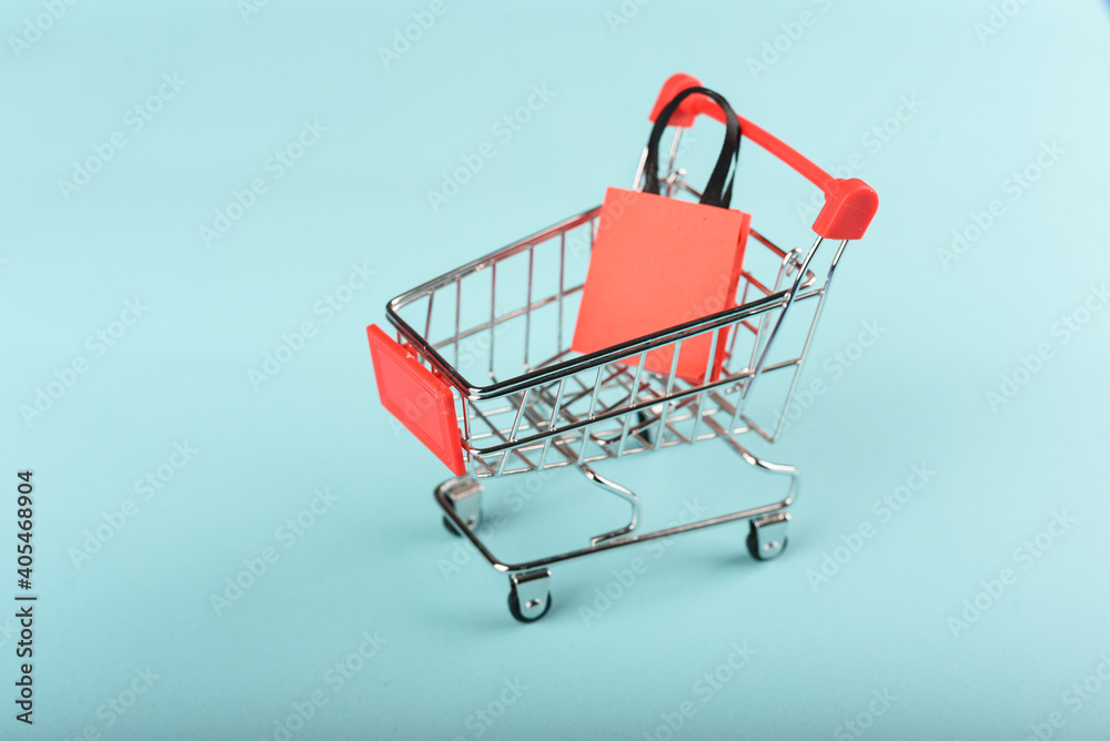 A miniature shopping cart carrying a shopping bag.