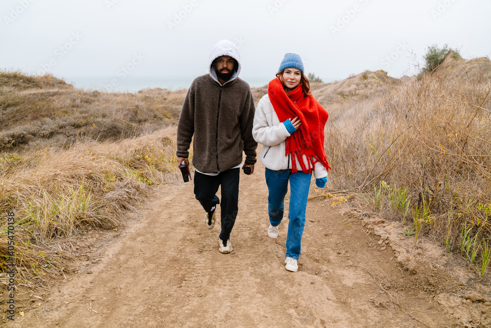 Attractive young multiethnic couple walking at the beachside