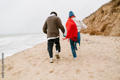 Happy young multiethnic couple walking at the beach