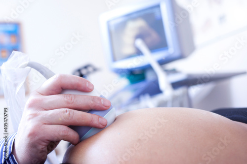Gynecologist checking female patient's fetal life signs with ultrasound scanner.