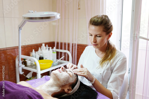 Face Lifting. Young woman getting facial scrub in the cosmetology salon