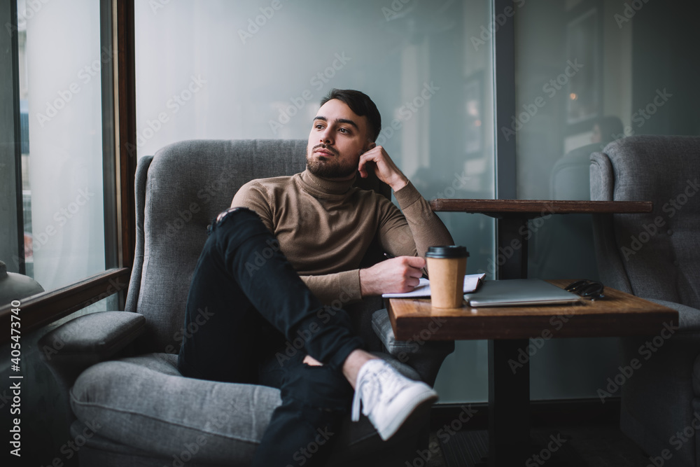 Thoughtful man with notebook on cozy chair Thoughtful man with notebook on cozy chair