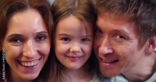 Close up portrait of happy smiling mother, father and little daughter