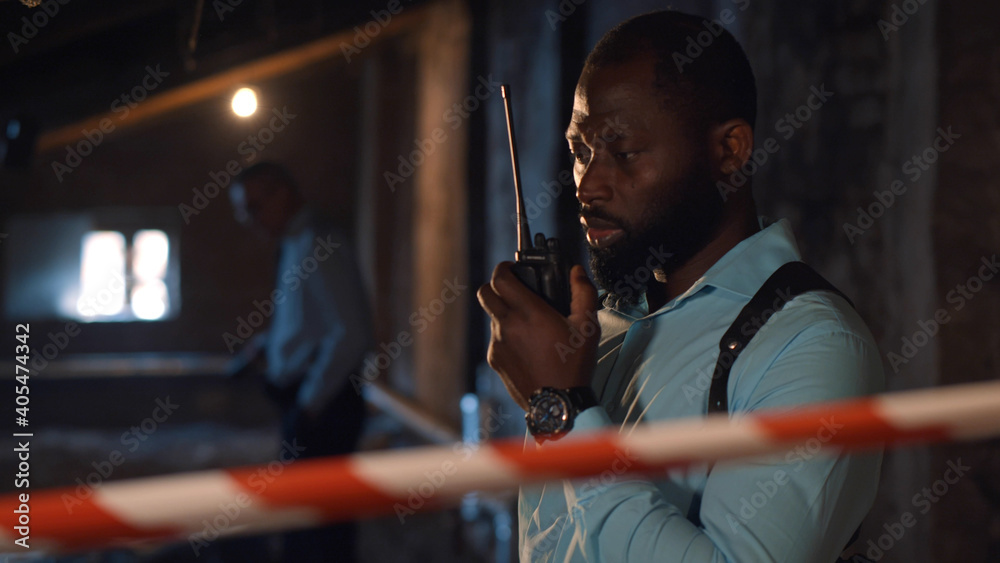 African policeman in talking on radio set at crime scene