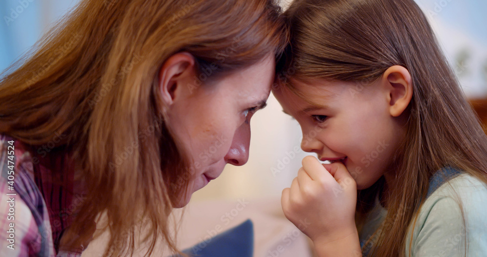 Joyful mom sitting with little girl on couch hugging and cuddling Joyful mom sitting with little girl on couch hugging and cuddling