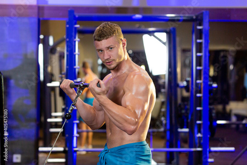 Blond male athlete performs fitness exercises in the gym