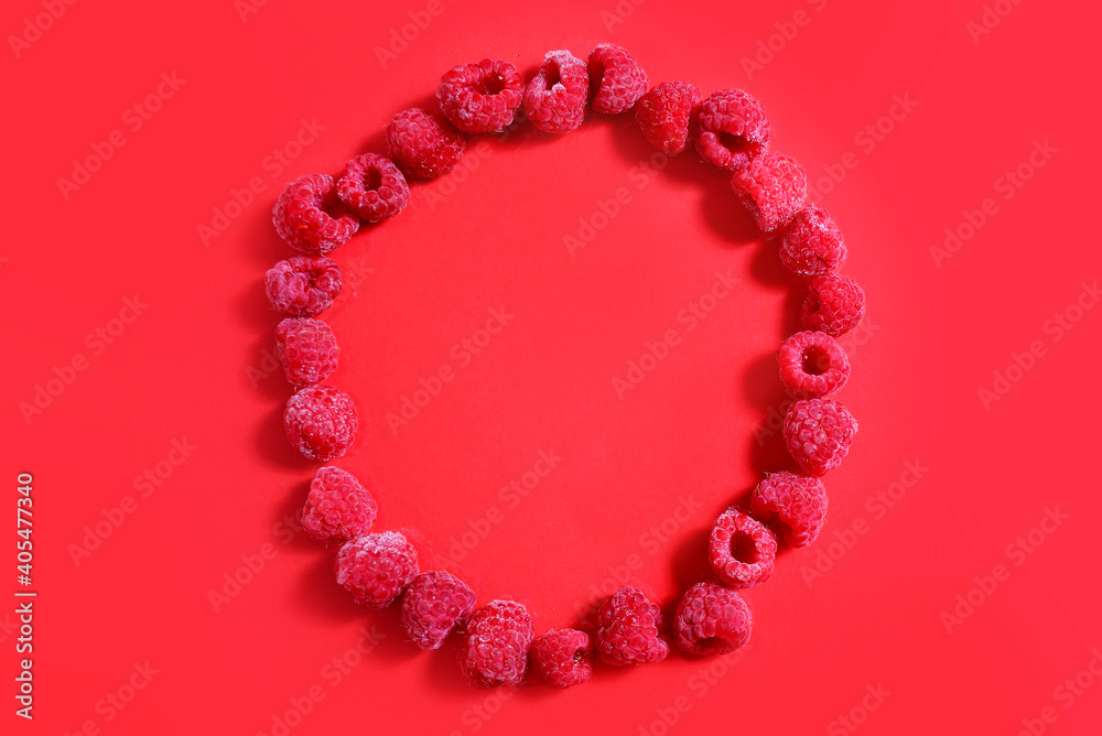 Berries of Frozen raspberries are laid out in a circle on a red background. frozen food concept. Top flat lay view. monochrome Berries of Frozen raspberries are laid out in a circle on a red background. frozen food concept. Top flat lay view. monochrome