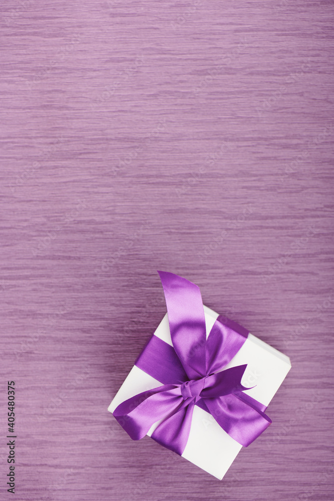 One gift box with purple bow on pink background. Vertical with copy space One gift box with purple bow on pink background. Vertical with copy space