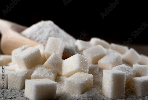 Pieces of refined sugar on a dark background. Sugar is scattered on the burlap