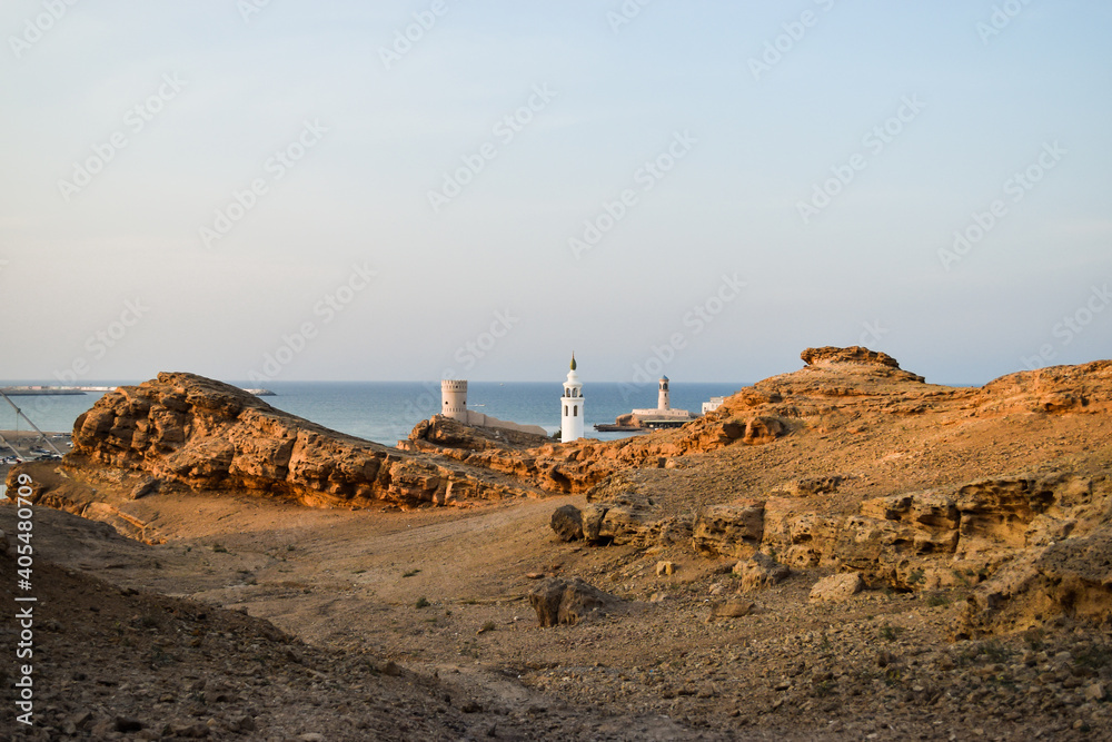 View of a tower, the minaret of a mosque and Al Ayjah Lighthouse from the mountains that surround it. Sur, Oman.