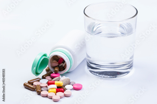 Medication bottle and white pills spilled on white background. Medication and prescription pills flat lay background. Opioid epidemic.