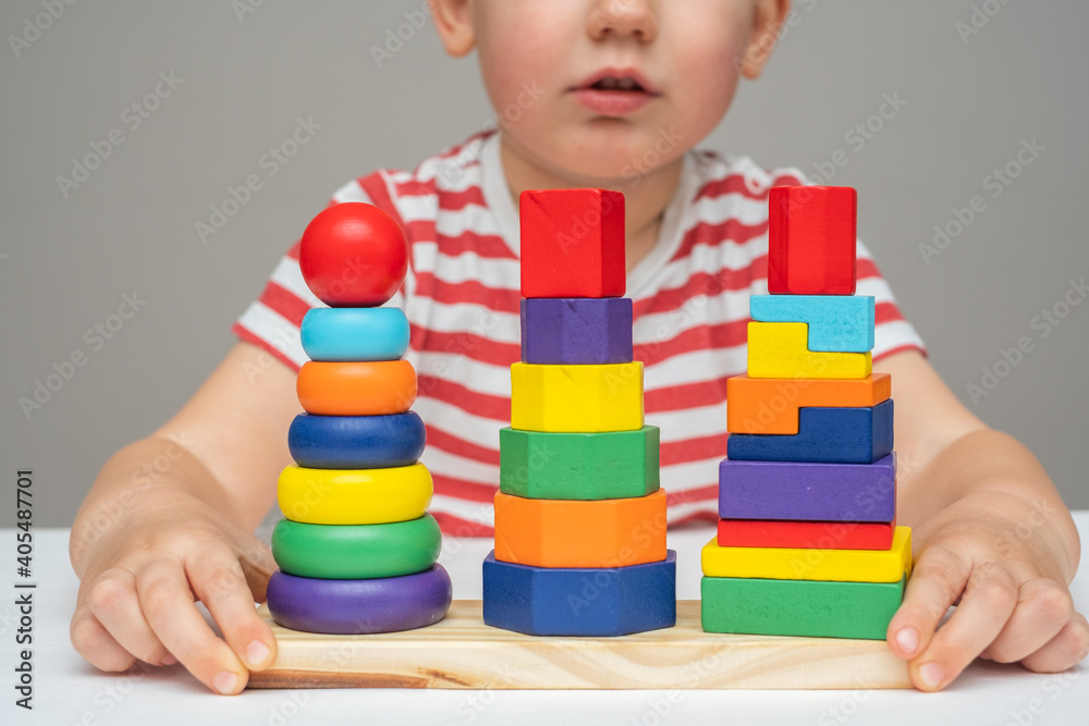 toddler plays with a developing multi-colored wooden toy pyramid. development of children. Hand motility. close-up toddler plays with a developing multi-colored wooden toy pyramid. development of children. Hand motility. close-up