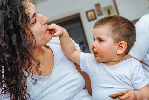 Boy eating chocolate while playing with mom