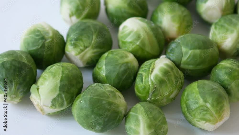 Slow Motion panning shot of fresh raw Brussels Sprouts on white background Slow Motion panning shot of fresh raw Brussels Sprouts on white background