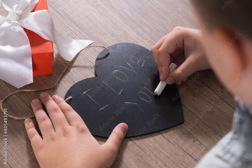 Child hands writes I love you on chalk board in form of heart. Congratulations for Mother's Day or Valentine's Day holiday. Child hands writes I love you on chalk board in form of heart. Congratulations for Mother's Day or Valentine's Day holiday.