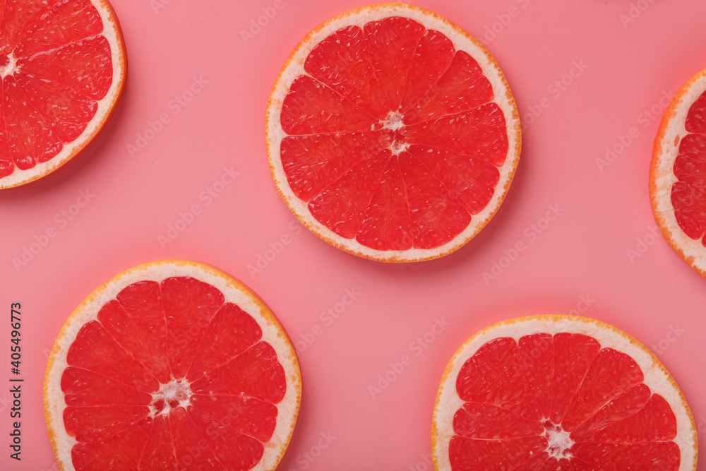 Patterns of slices of juicy grapefruit on a pink background, a beautiful pattern.