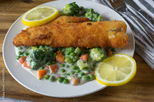 Pan fried fish with mixed vegetable and sauce on a plate