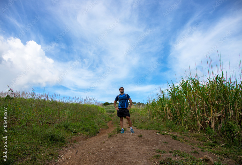 Trekker on trail on natural landscape background. Summer countryside hiking trail view with male tourist. Man in treking or hiking outfit. Active lifestyle. Sport fit look in nature