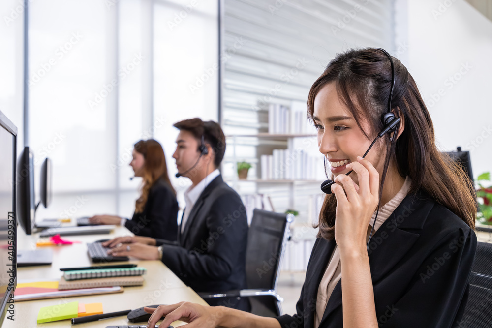 Young Asian female customer service support agent operator team working in call center office with headsets and computer. Young Asian female customer service support agent operator team working in call center office with headsets and computer.