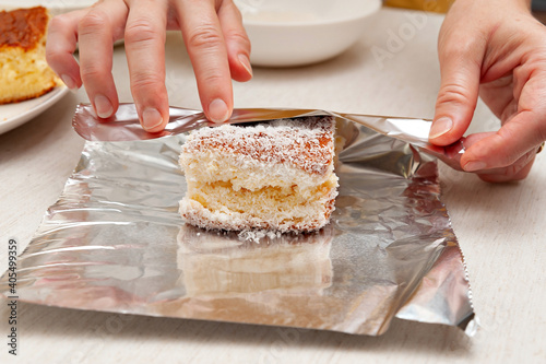 BOLO GELADO is a traditional Brazilian cake - Wrapping the cake with coconut sprinkles in aluminum foil. Front view.