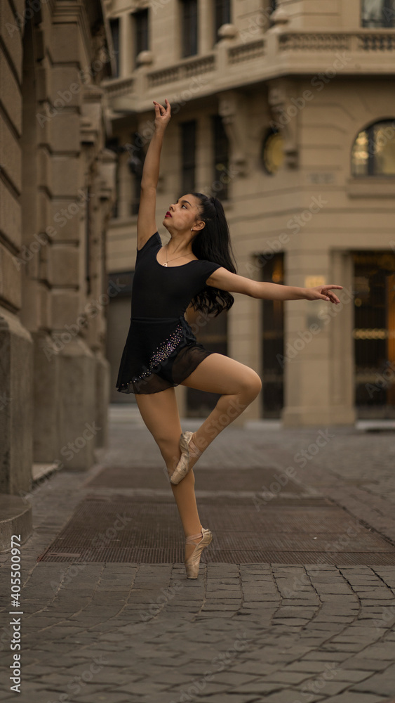 Latin teen girl dancing or posing as ballet dancer at sunset on the street of new york-like building