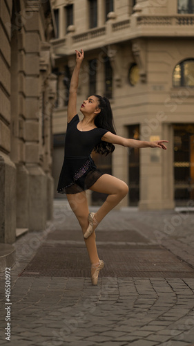 Latin teen girl dancing or posing as ballet dancer at sunset on the street of new york-like building