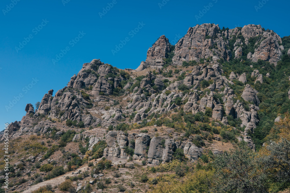 Ridge of brown rocks covered with greenery against a blue sky