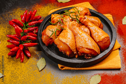 Marinated Chicken Drumstick on Black Ceramic Round Roasting Plate Raw Chicken for Grilling with Spices for Cooking.Top view.Convenience food,pree cooked photo