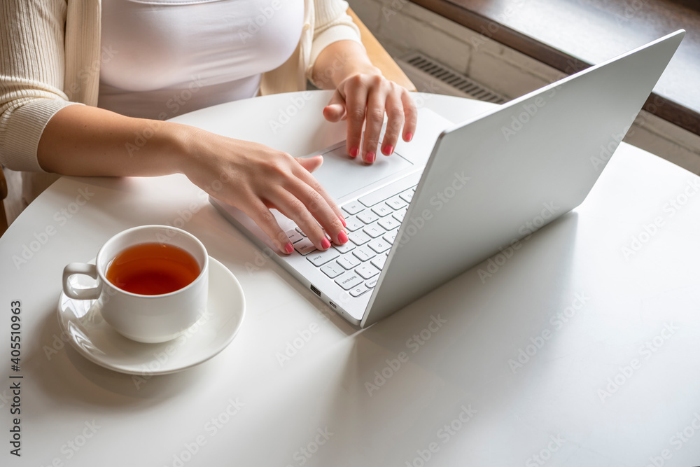 Lonely woman freelancer enjoying having breakfast with cup of coffee working on laptop sitting near window in cafe at morning. View on bust of female Lonely woman freelancer enjoying having breakfast with cup of coffee working on laptop sitting near window in cafe at morning. View on bust of female