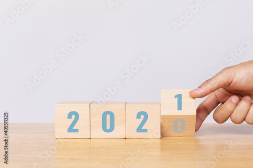 Hand flip wooden cube with the number 2020 to number 2021 on white background. Merry Christmas and happy new year concept