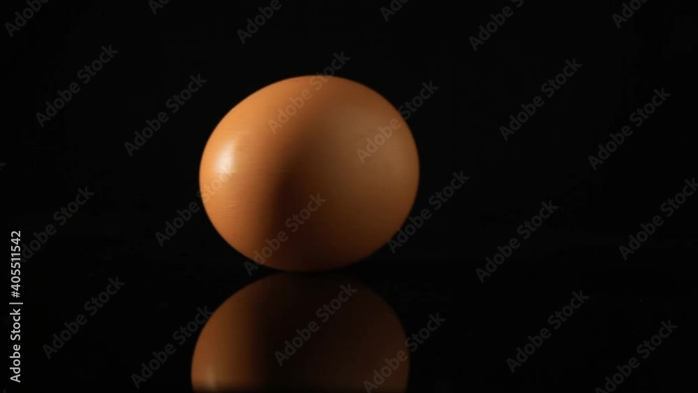 Spinning the raw egg on black background, Low contrast light, Idea for Insert shot of an egg, close up shot, food stylist Spinning the raw egg on black background, Low contrast light, Idea for Insert shot of an egg, close up shot, food stylist