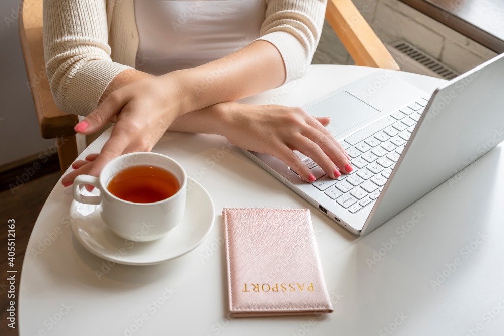 Woman with passport and laptop, cup of coffee sitting in cafe near window. making order and booking. Online service. concept. Woman with passport and laptop, cup of coffee sitting in cafe near window. making order and booking. Online service. concept.