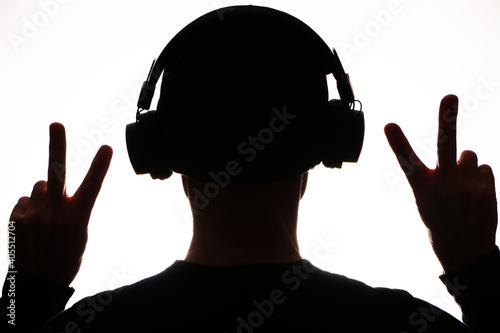 Wireless technology - Dark silhouette in headphones listens to music on a white background.