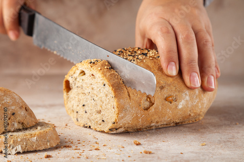 Close-up baker hands, chopping cereal bread with knife