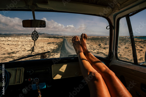 Travel and freedom concept people with close up of woman legs enjoy the road trip inside an old vintage van - vanlife lifestyle girl with long road asphalt in background