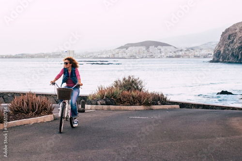 Woman ride the bike outdoor with coast ocean view - healthy transport lifestyle green environment and world respect people - tourist enjoy the vacation riding on the road