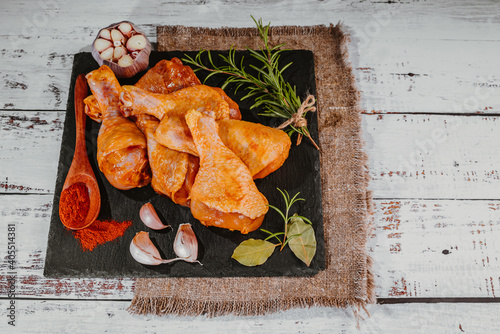 Marinated chicken dramstick on a black ceramic plate. Raw chicken for grilling with spices for cooking.Top view.Convenience food,pree cooked photo