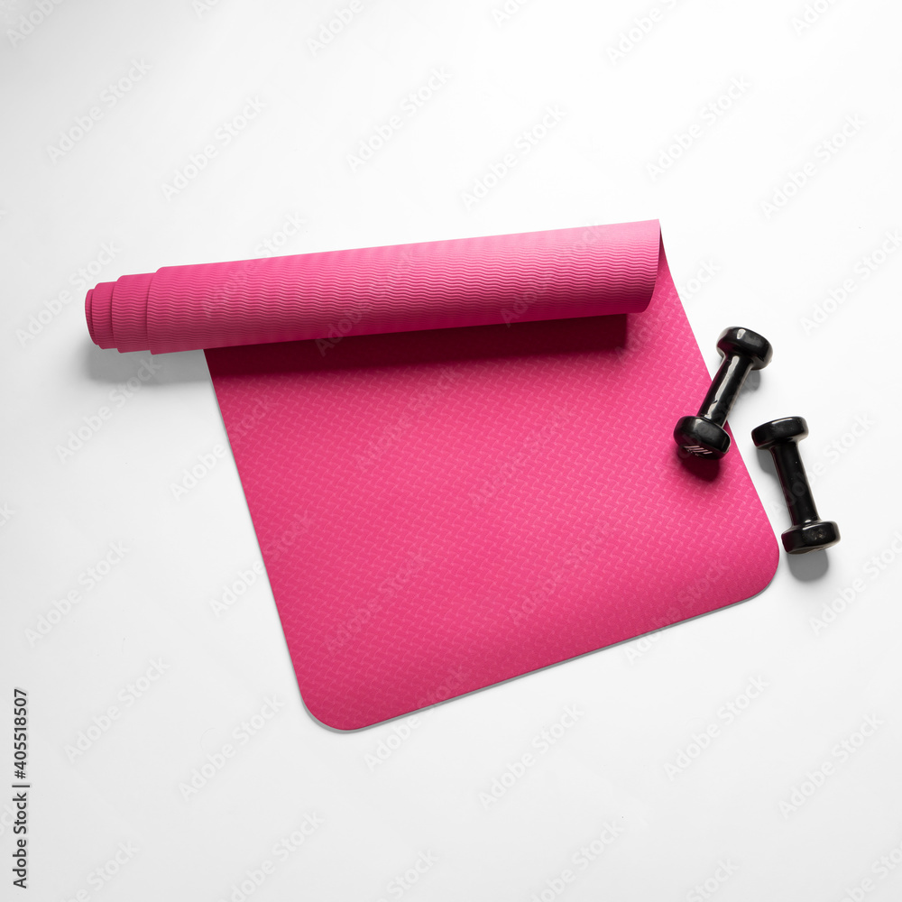 Top view of a pink fitness mat and two black dumbbells isolated on a white background - obrazy, fototapety, plakaty 