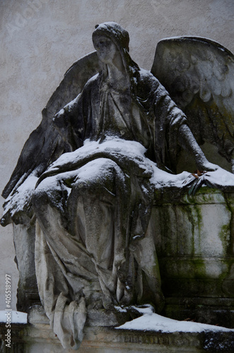 Tombstones and graves, family crypts and vaults on graveyard or cemetery with angels, saints and other statues in winter with snow and lots of symbols and symbolism of eternety and death photo