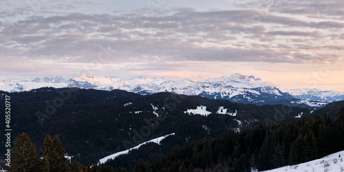 panorama sur la chaine du Mont Blanc enneigée dans les Alpes françaises au coucher du soleil depuis la station des Gets en France.