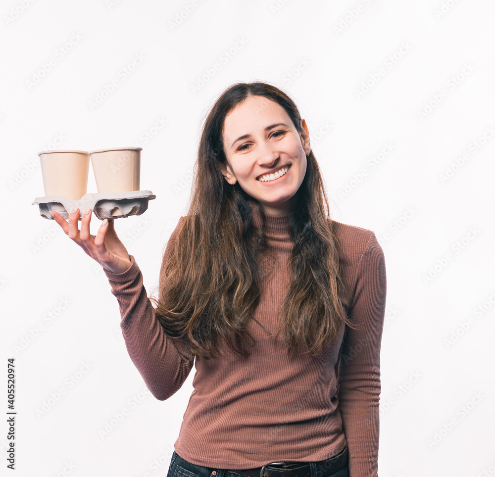 Photo of smiling young woman holding two cups of coffee to go. Photo of smiling young woman holding two cups of coffee to go.
