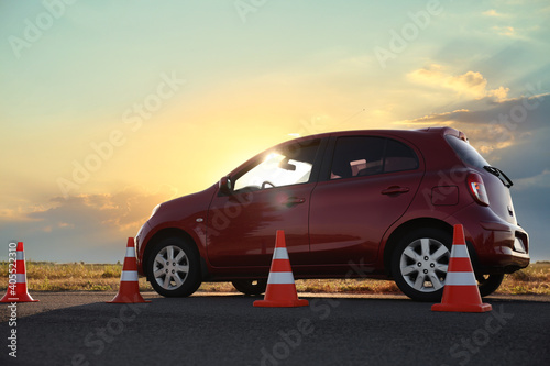 Traffic cones near red car outdoors. Driving school exam © New Africa