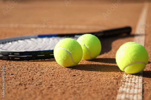 Tennis balls and racket on clay court © New Africa