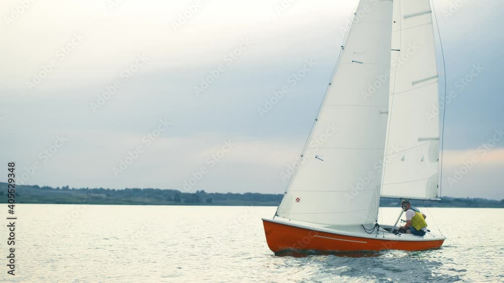 Sailing at racing yacht open sea, sunshine aerial view. Majestic seascape with blue cloudy sky background. Alone man riding at the yacht. Luxury lifestyle cinematic scene. Trip, yacht sport concept