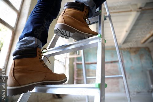 Professional constructor on ladder in old building, closeup photo